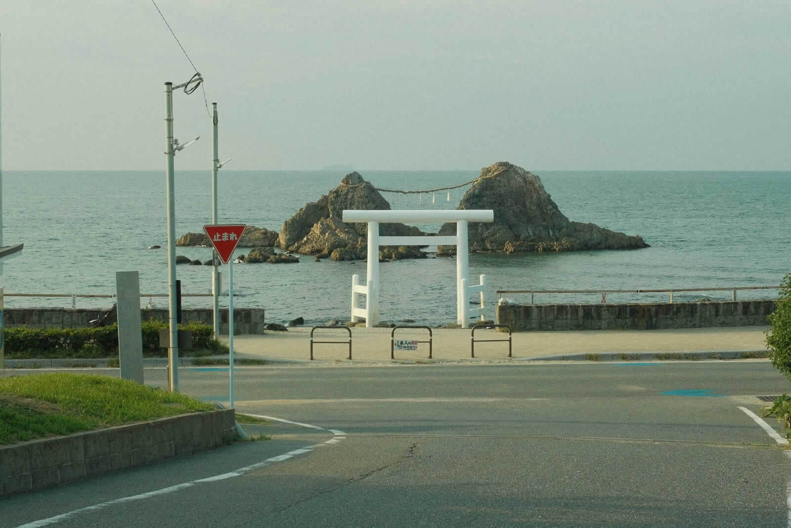 鎌倉高校前の海岸道路の先に、白い鳥居と夫婦岩が見える風景