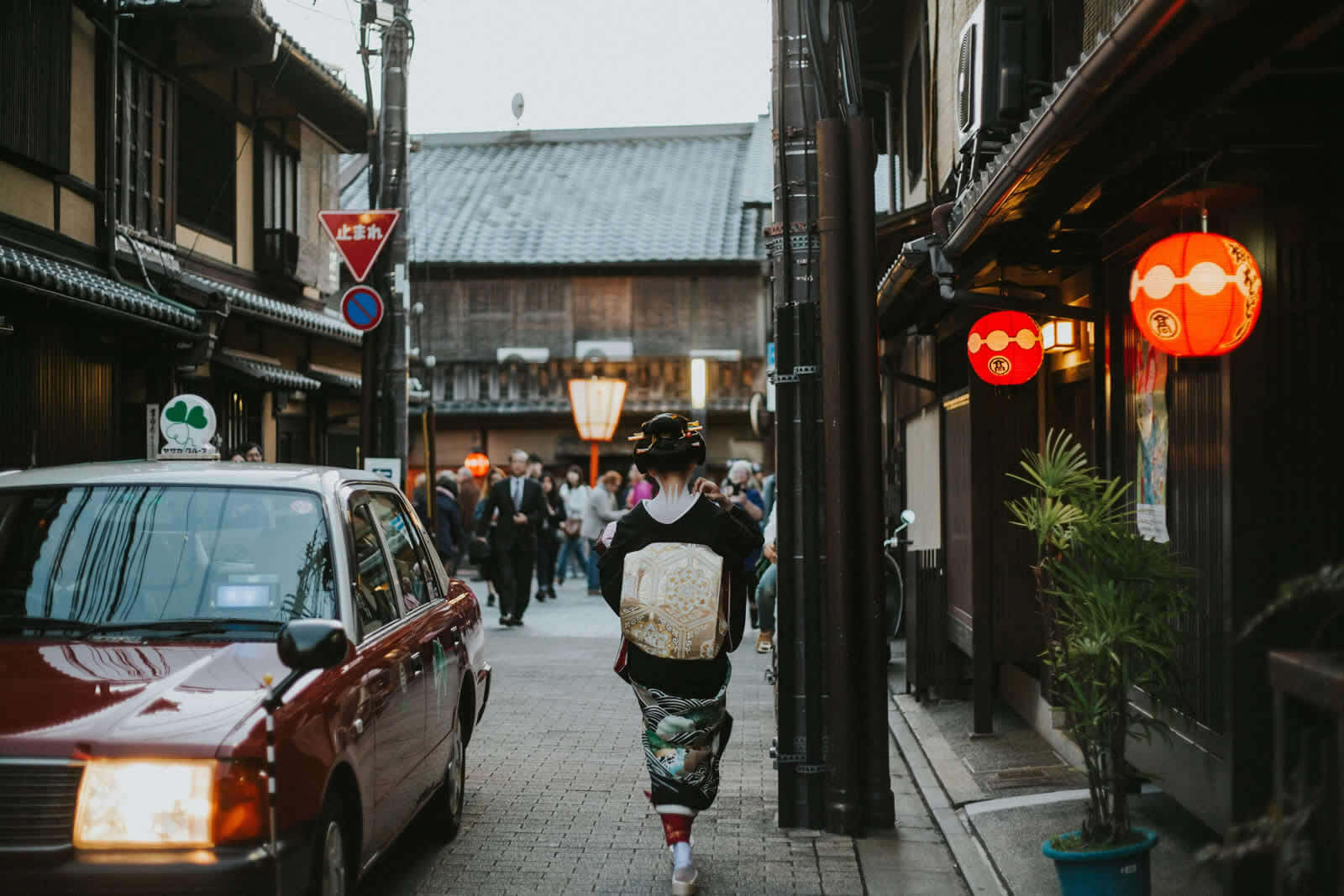 舞妓が京都・祇園の石畳の路地を歩く夕暮れ時